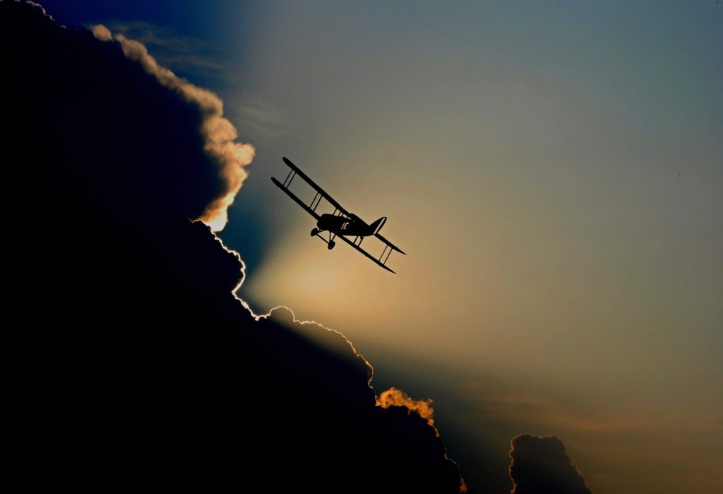 Biplane flying through clouds and a sunset